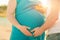 Male hands are holding a pregnant belly closeup and copy space. Pregnant in a blue dress and a calendar in hand, the concept of th