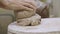 Male hands knead and form soft piece of grey clay. Preparation of clay material for making handmade pots. Masterclass in