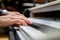 Male hands with long fingers playing music on keyboard with white and black keys of a piano