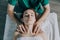 The male hands of the masseur massage the shoulder girdle and neck to a young woman.