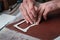 Male hands of master cutting with a knife pattern from genuine leather