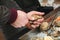 Male hands open oysters with a knife, close up. Fish market showcase full of fresh oysters and shrimps. Seafood market