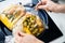 Male hands opening plant based baked dish with brussels sprouts, parsley root, corn. Mixed vegetables in a baking bag on