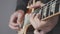 Male hands playing on electric guitar close up. Fingers on guitar fretboard holding pick and playing chords and solo. Musical inst