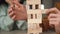 of male hands pulling wooden block of jenga game. Tower made of wooden blocks and human hands take one block