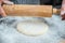 Male hands rolling out dough on the table