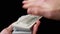 Male Hands Scatter Stack of 100 US Dollar Bills on Black Background. Money. 4K