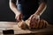 Male hands slicing home-made bread on the wooden board