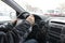 Male hands on the steering wheel of a car on a winter urban road