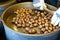 Male hands stirring and roasting delicious organic chestnuts on a gas barrel stove with wooden ladle