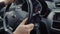 Male hands are turning steering wheel of modern automobile, close-up view