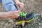 Male hands tying up shoelaces on a running sneaker, close up. Part of sportsman tying sneakers. Leg on a rock.