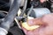 Male hands unscrew the fuel line from the fuel filter with a phillips screwdriver to replace it. Closeup view