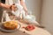 Male hands whipping whites cream in glass bowl with mixer on wooden table. Making sponge cake or red velvet cake