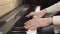 Male hands with white sleeves play the digital piano.