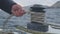 Male hands of yachtsman pull and reel up ropes on board sailing yacht close up