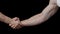 Male handshake. Gestures. Black background. Man\'s hands. Greetings and farewell.