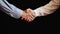 Male handshake. One hand in a shirt, the other in a sweater. Small business. Agreement. Partnership. Black background