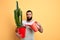 Male handsome bearded florist watering house plant on yellow background