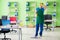 The male handsome professional cleaner doing mopping in the office