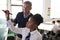 Male High School Teacher With Female Student Wearing Uniform Using Interactive Whiteboard During Lesson