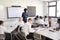 Male High School Teacher Standing Next To Interactive Whiteboard And Teaching Lesson To Pupils Wearing Uniform