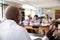 Male High School Tutor At Desk Teaching Students In Biology Class