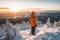 Male hiker admiring a scenic view from a snowy mountain top. Adventurous young man with a backpack. Hiking and trekking on a