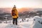 Male hiker admiring a scenic view from a snowy mountain top. Adventurous young man with a backpack. Hiking and trekking on a