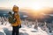 Male hiker admiring a scenic view from a snowy mountain top. Adventurous young man with a backpack. Hiking and trekking on a