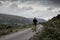 A male hiker with backpack running away from the camera, on a mountain lane. With a horror edit