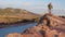 Male hiker with a backpack and trekking poles on a cliff