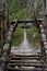 Male hiker crossing wooden fragile footbridge