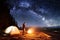 Male hiker have a rest in his camp near the forest at night under beautiful night sky full of stars and milky way