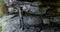 Male hiker looking through binoculars near a cave 4k