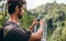 Male hiker photographing a water fall in forest