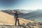 Male hiker relaxing at sunset at the mountain summit and looking at majestic panorama of the italian Alps with dirt road crossing