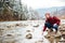 Male hiker sitting on the stone and testing wate