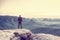 Male hiker stand on edge and enjoying dramatic overlook of misty landscape. The Sun is hidden in thick mist and change colors