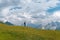 Male hiker walk far in the long distance, on a summer sunny day, against the background of snow-capped peaks of the Caucasus