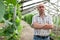 Male horticulturist near cucumber seedlings in hothouse