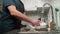 Male housewife washes a plate under running water in the sink in modern kitchen