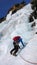 Male ice climber in a blue jacket on a gorgeous frozen waterfall climbing in the Alps in deep winter