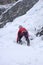 Male ice climber in heavy snowfall and bad weather climbing a frozen waterfall in the Swiss Alps