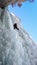 Male ice climber on the last pitch of a very hard and steep ice fall in a narrow rock gully in the Alps