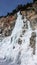 Male ice climber on a steep frozen waterfall on a beautiful winter day in the Swiss Alps