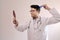 Male indian doctor in white coat and stethoscope combing hair by looking at mirror