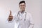 Male indian doctor in white coat and stethoscope showing thumbs up in confidence