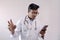 Male indian doctor in white coat and stethoscope in worried expression while looking at smart phone