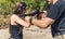 Male instructor helping female client wearing safety goggles and headphones use submachine gun. Firearm training